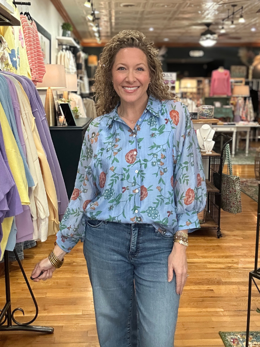Woman wearing a floral blouse and jeans in a store setting