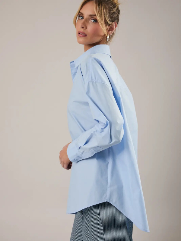 Woman wearing a light blue shirt with a plain background