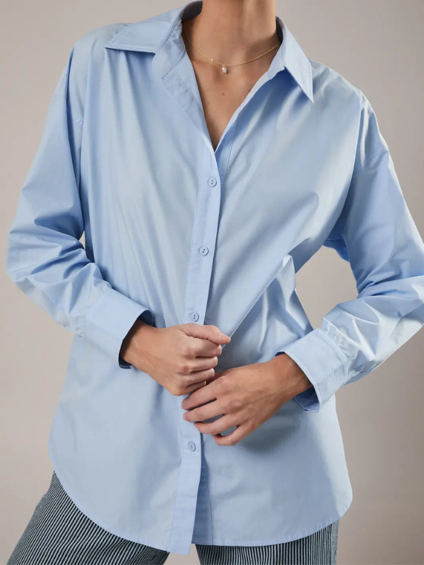 Person wearing a light blue button-up shirt against a neutral background