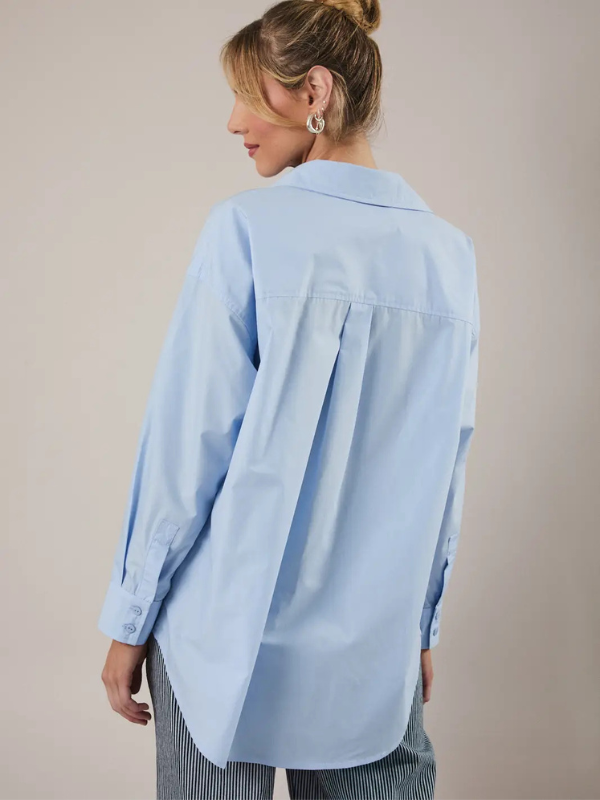 Person wearing a light blue shirt against a beige background