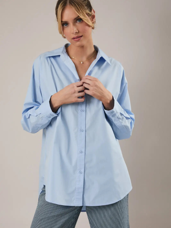 Woman wearing a light blue shirt against a beige background