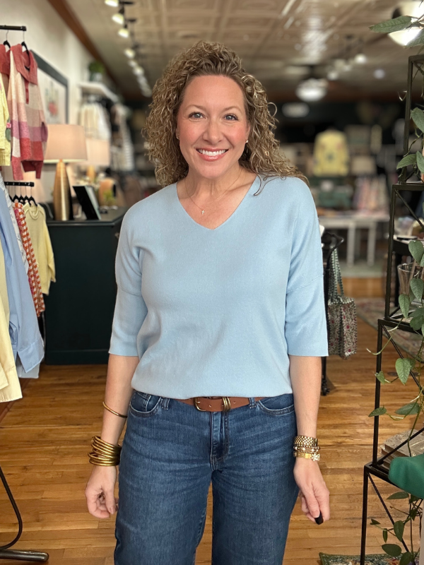 Woman wearing a light blue sweater and jeans in a store setting