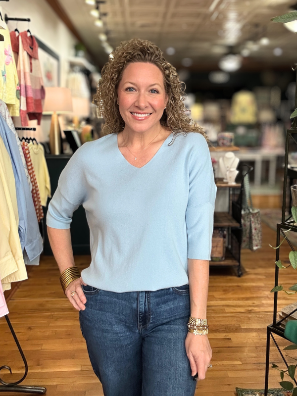 Woman wearing a light blue shirt and jeans in a store setting