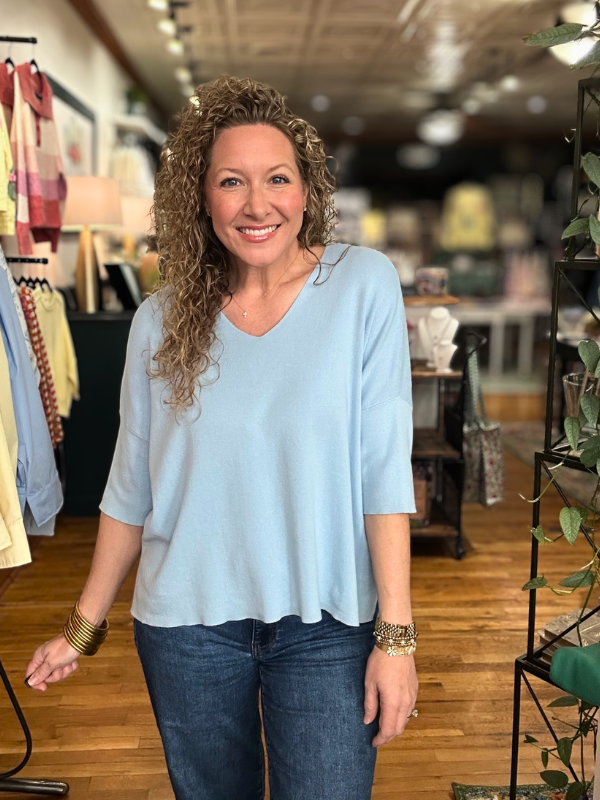 Woman wearing a light blue shirt and jeans in a store setting