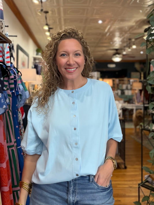Woman wearing a light blue shirt and jeans standing in a store.