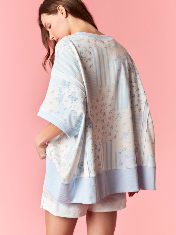 Woman wearing a light blue floral kimono-style garment on a pink background