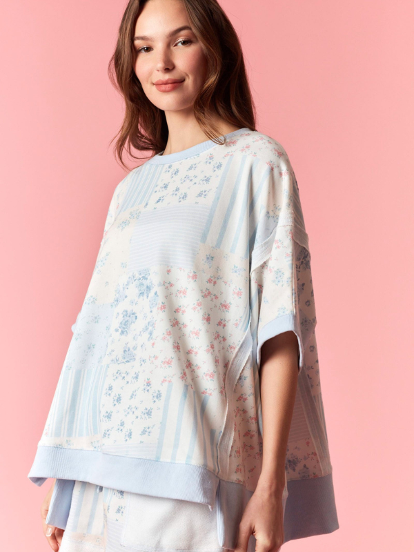 Woman wearing a floral patterned poncho against a pink background