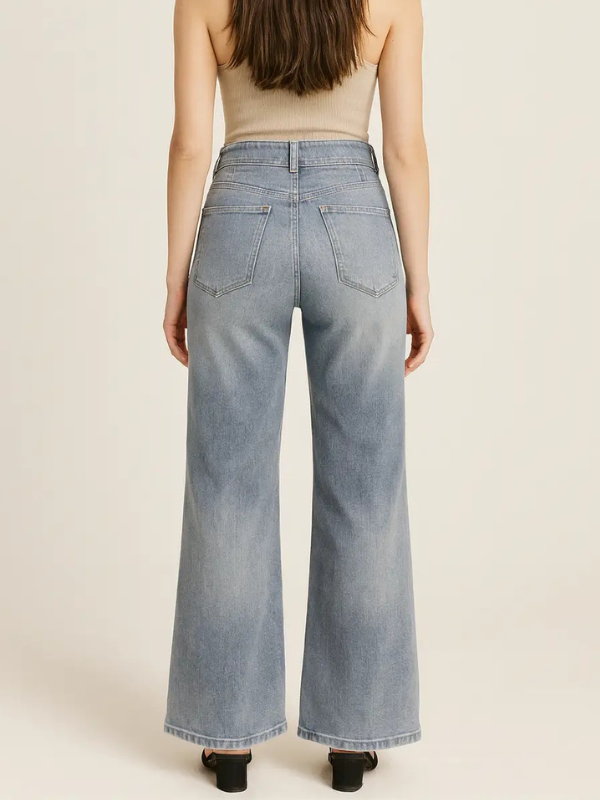 Person wearing light blue wide-leg jeans on a beige background