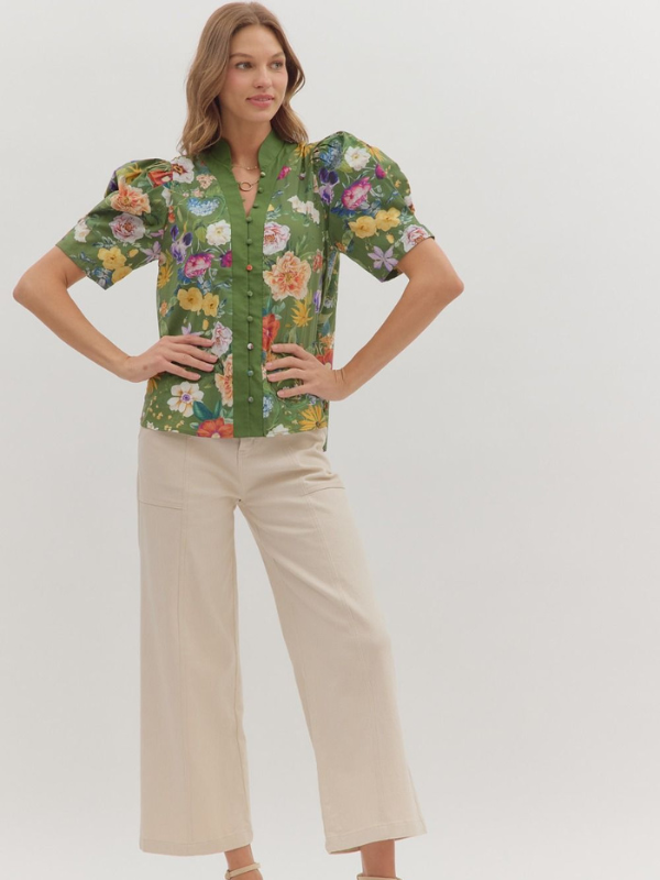 Woman wearing a floral blouse and beige pants on a white background