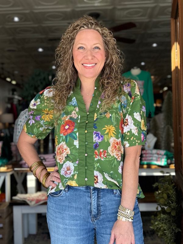 Woman wearing a green floral shirt in an indoor setting