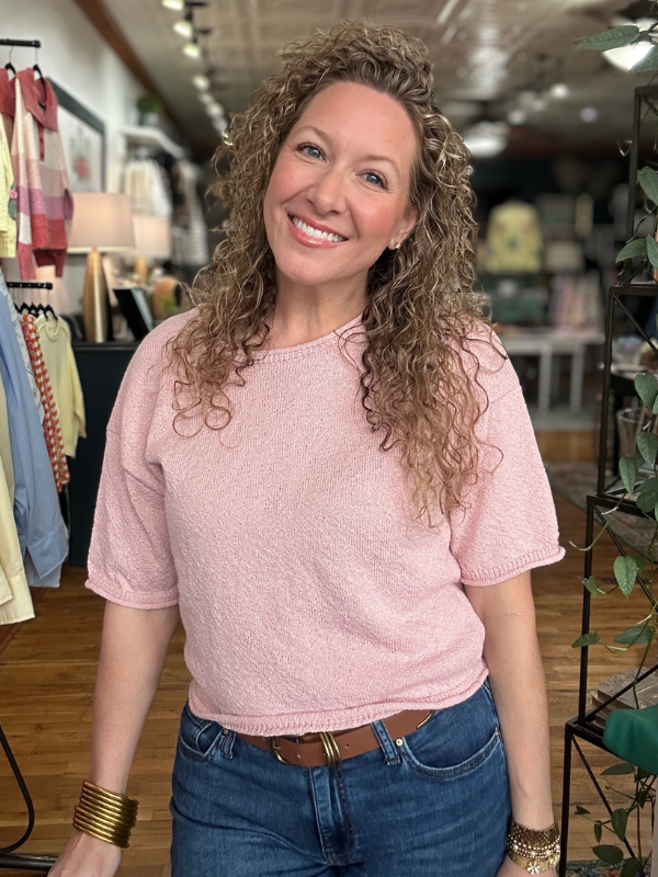 Woman wearing a pink sweater and blue jeans in a store setting