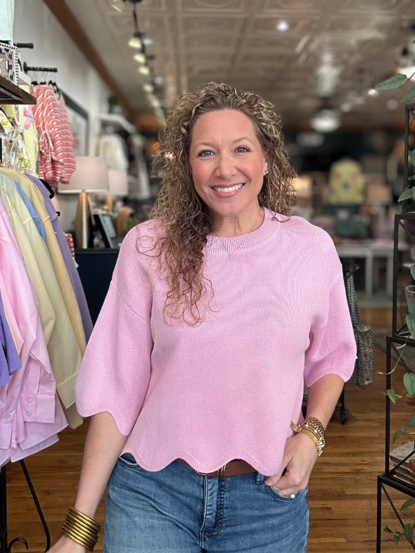 Woman wearing a pink sweater and blue jeans in a store setting