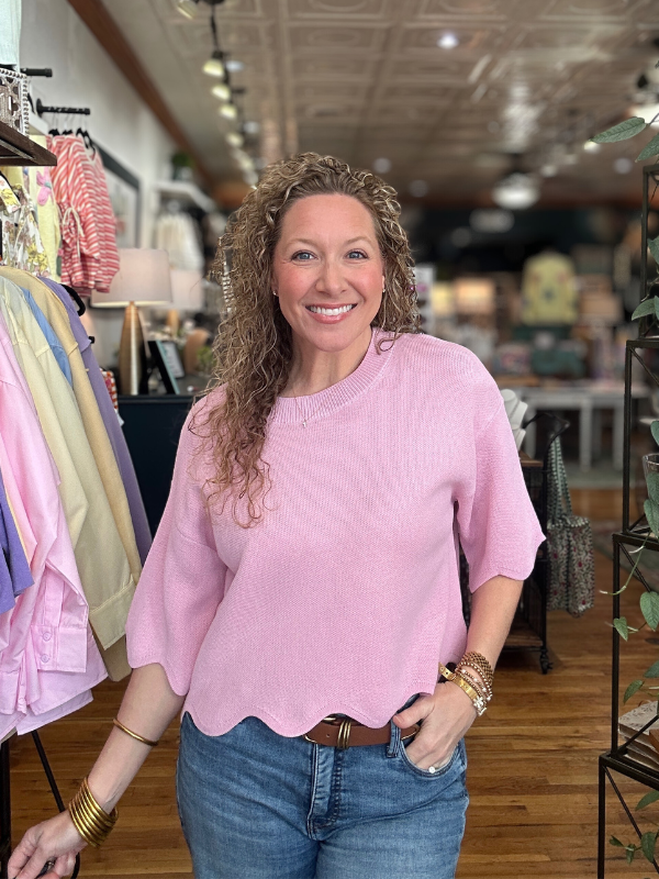 Woman wearing a pink sweater and blue jeans in a store setting