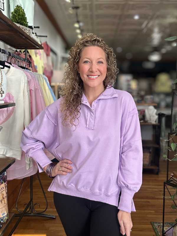 Woman wearing a light purple sweatshirt in a store setting
