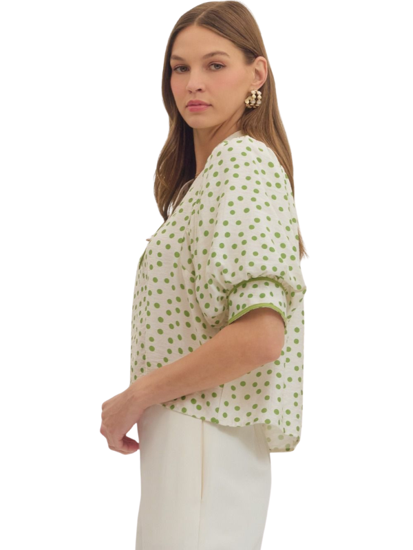 Woman wearing a green polka dot blouse on a white background