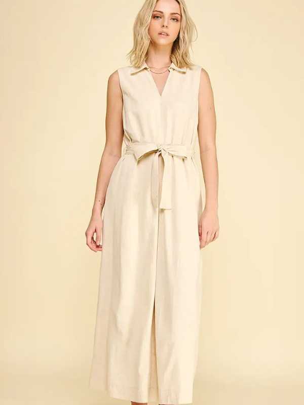 Woman wearing a beige sleeveless dress against a yellow background