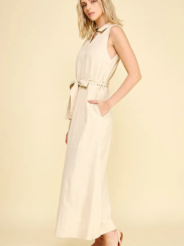 Woman wearing a beige sleeveless dress with a belt on a light yellow background