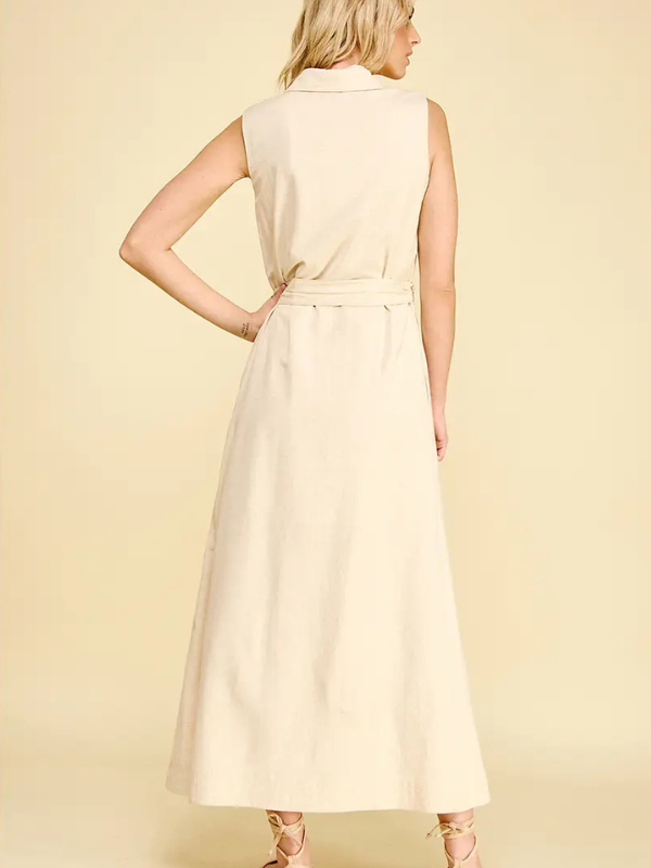 Woman wearing a light-colored sleeveless dress against a plain background
