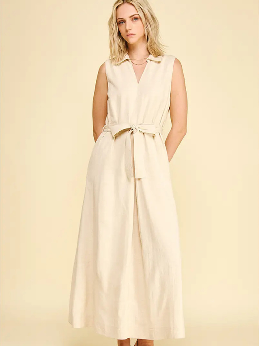 Woman wearing a beige sleeveless dress with a belt on a light yellow background