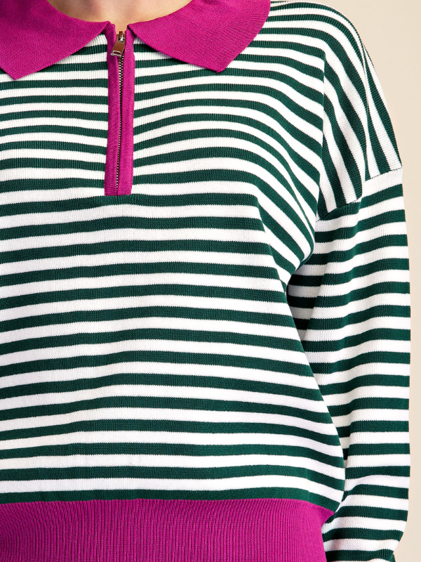 Close-up of a striped knit top with dark green and white horizontal stripes, a bright pink collar, and a matching pink zipper placket.