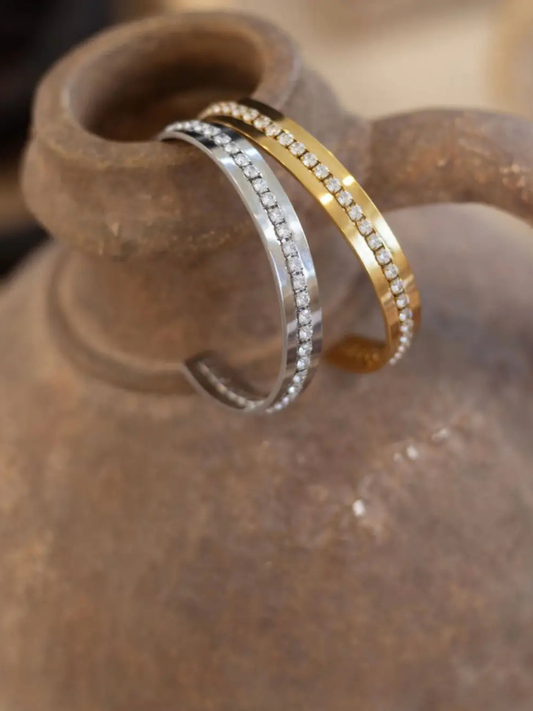 Two rings, one gold and one silver, on a textured surface.