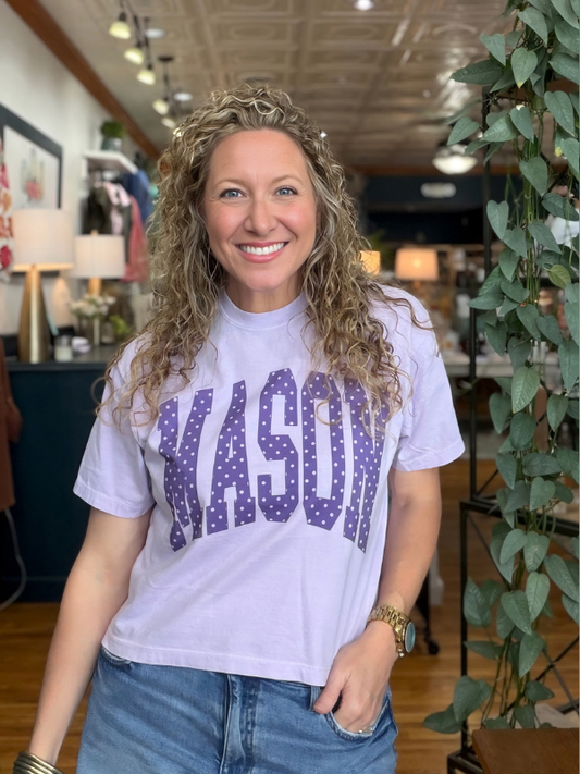 woman wearing an orchid boxy top with polka dot words saying Mason 