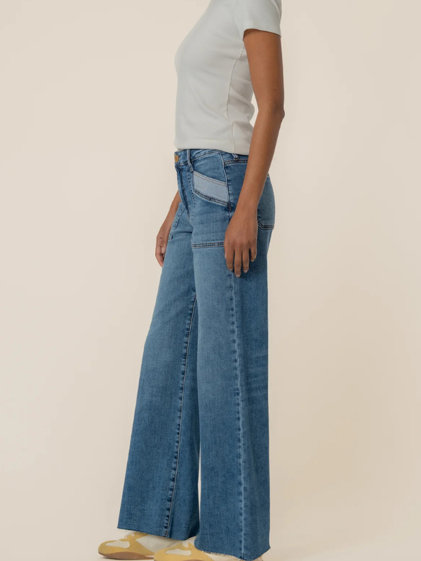 Person wearing blue jeans and a light gray shirt on a beige background