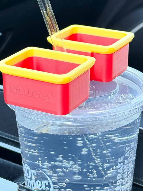Two red and yellow suction cup holders on a clear cup with bubbles.