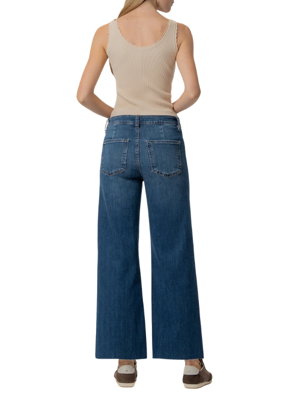 A woman shown from the back wearing blue wide-leg jeans, a beige ribbed tank top, and brown shoes against a plain white background.