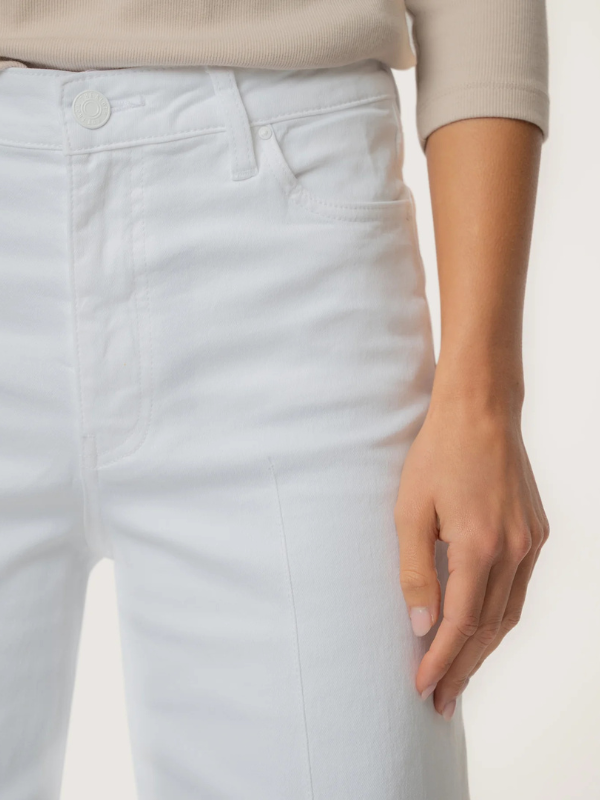 Person wearing a beige sweater and light white pants on a white background