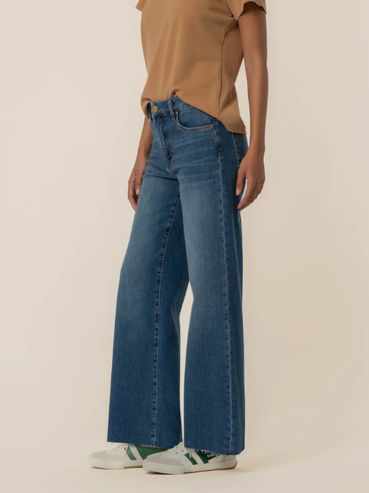 Person wearing blue jeans and a brown shirt on a beige background