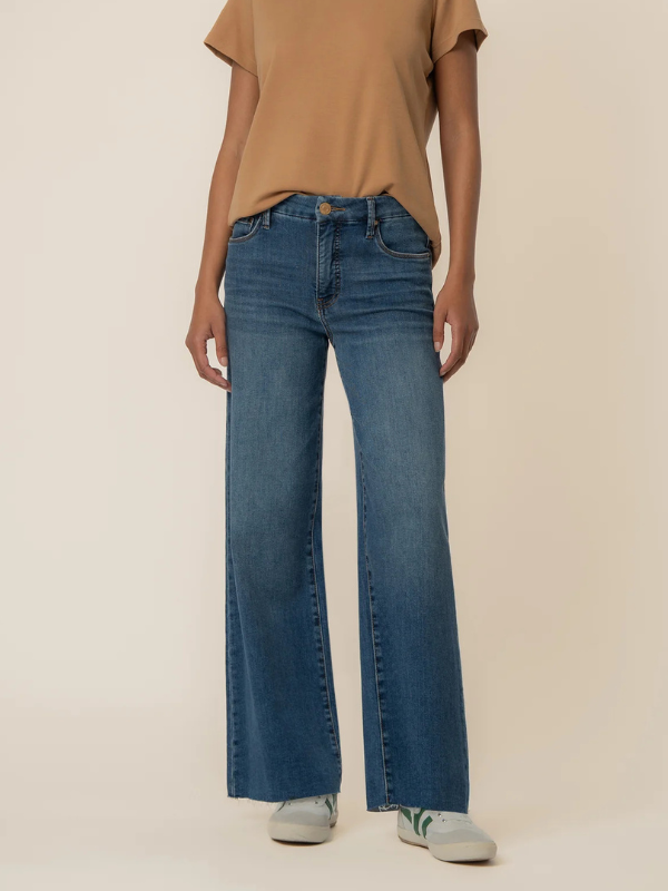 Person wearing blue jeans and a brown top on a beige background