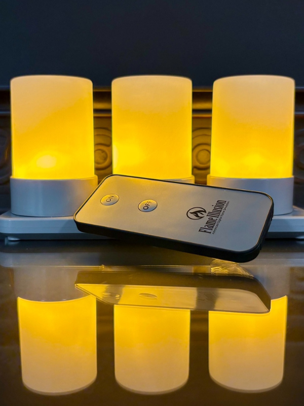 Three glowing cylindrical lights with a remote control on a reflective surface.