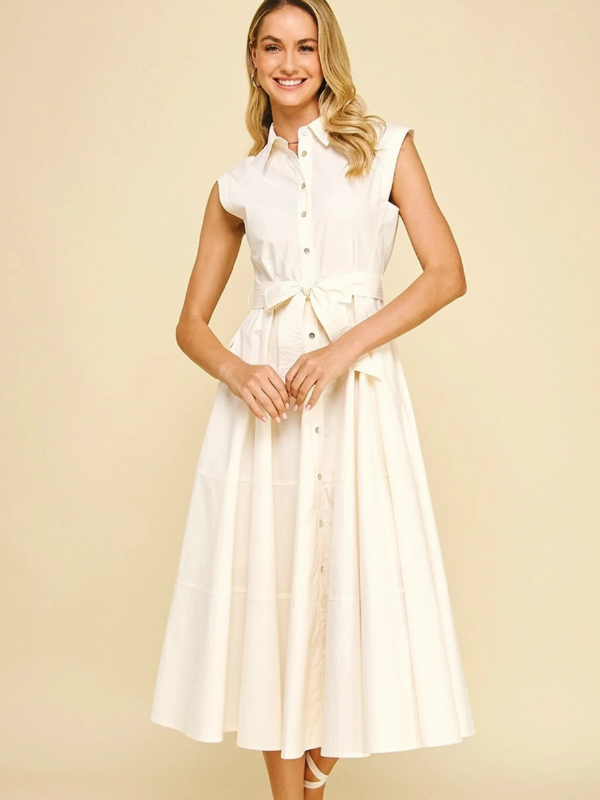 Woman wearing a white dress with a belt on a beige background