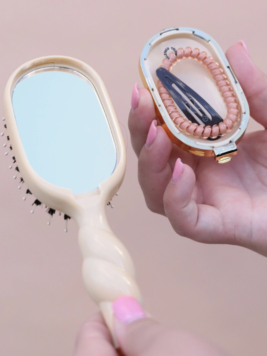 Close-up of a hairbrush with a mirror and a small model of a digestive system.