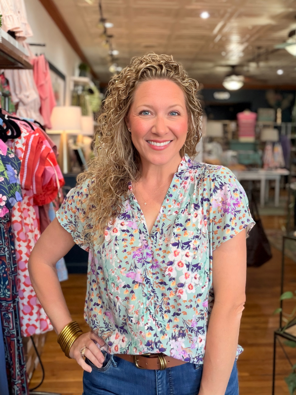 Woman in a floral blouse standing in a clothing store
