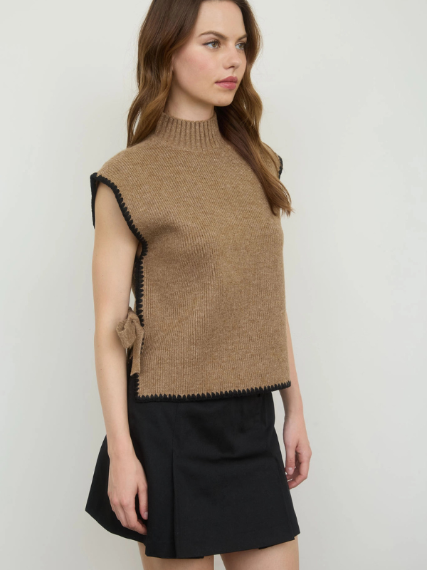 Woman wearing a brown knitted vest with black trim on a white background