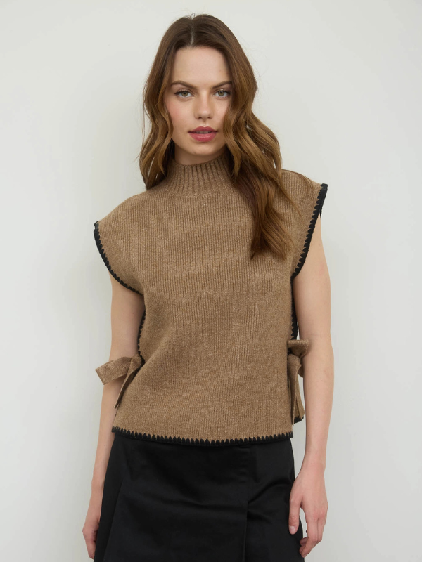 Woman wearing a brown sleeveless knit top against a plain background