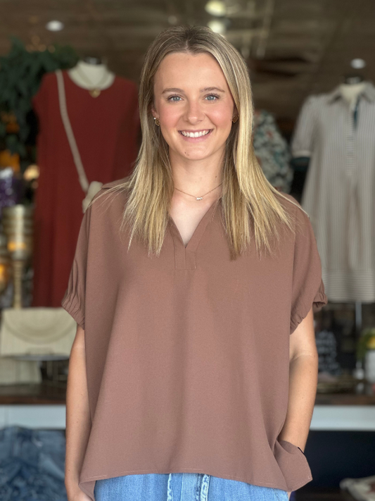 Woman wearing a brown blouse in a clothing store setting