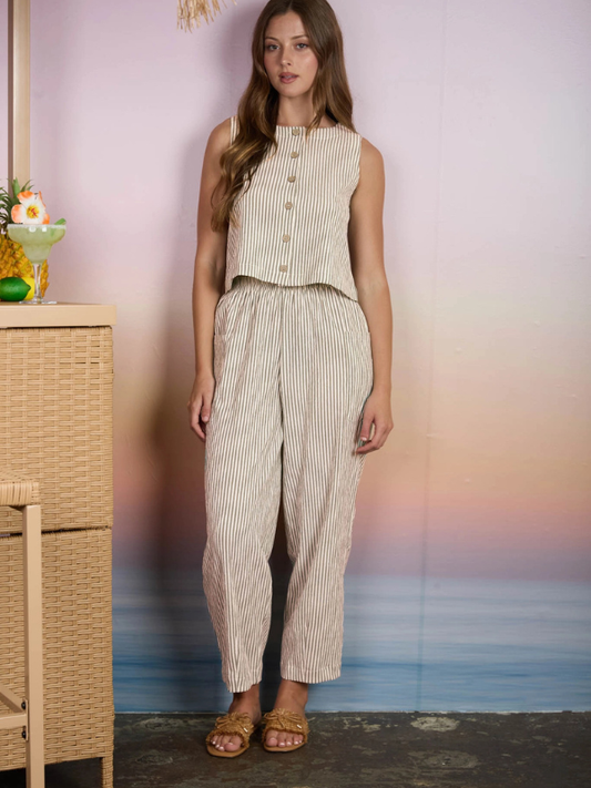 Woman wearing a striped outfit standing in front of a blurred beach scene