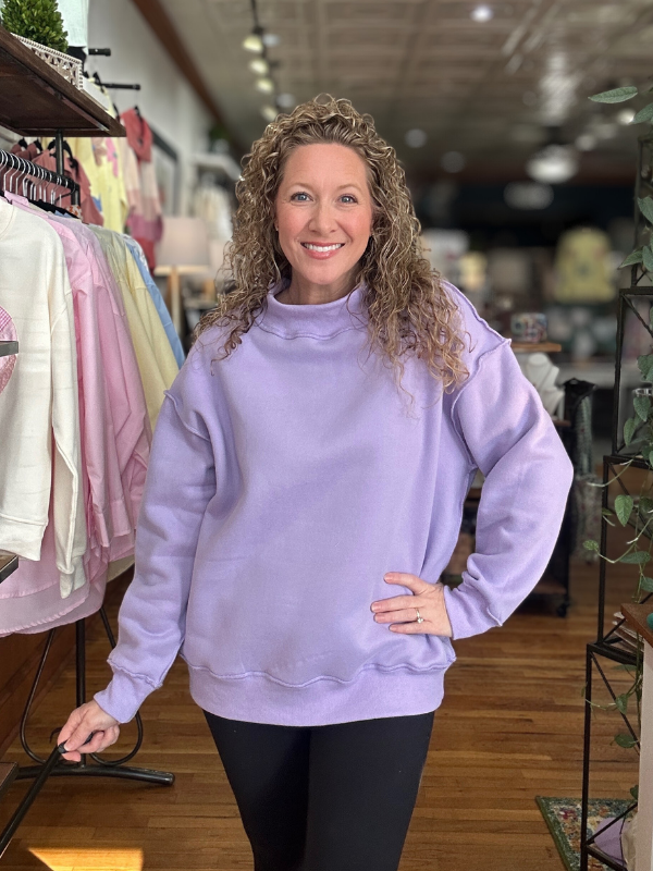 Woman wearing a light purple sweatshirt in a clothing store.