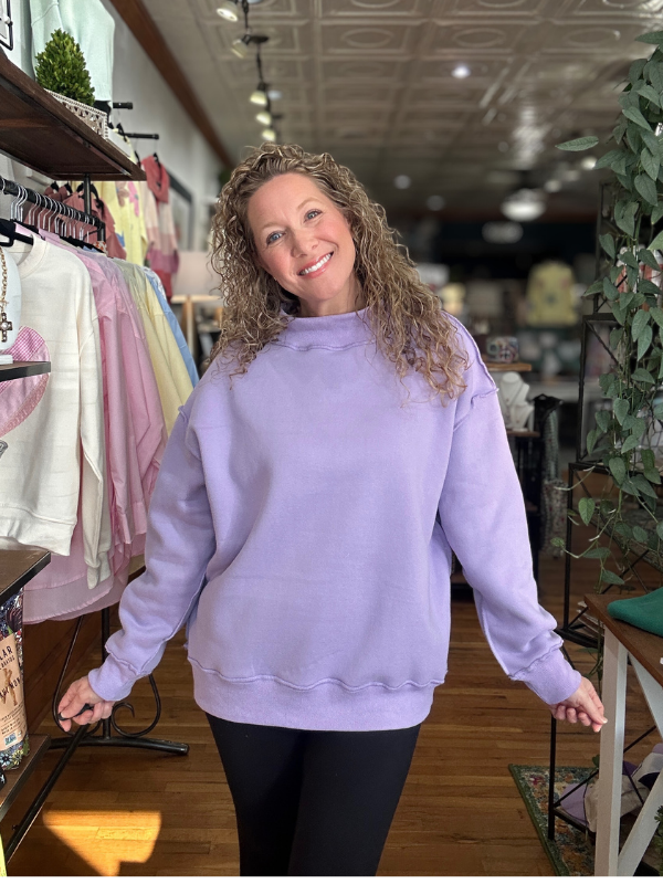 Woman wearing a light purple sweatshirt in a store setting