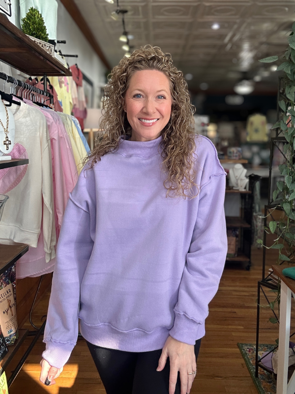 Woman wearing a purple sweatshirt in a store setting