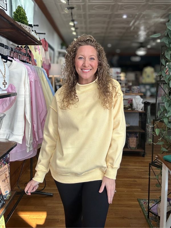 Woman wearing a yellow sweatshirt in a store setting