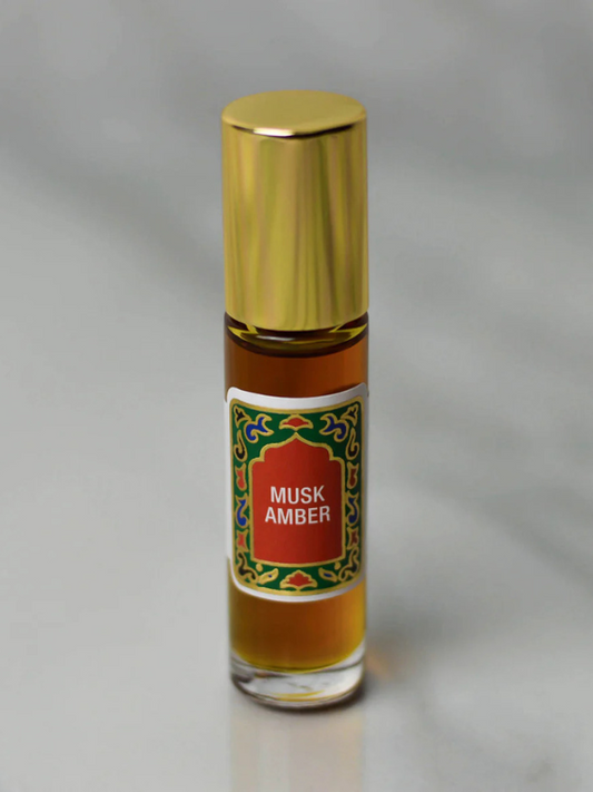 Bottle of Musk Amber perfume with gold cap on a gray background
