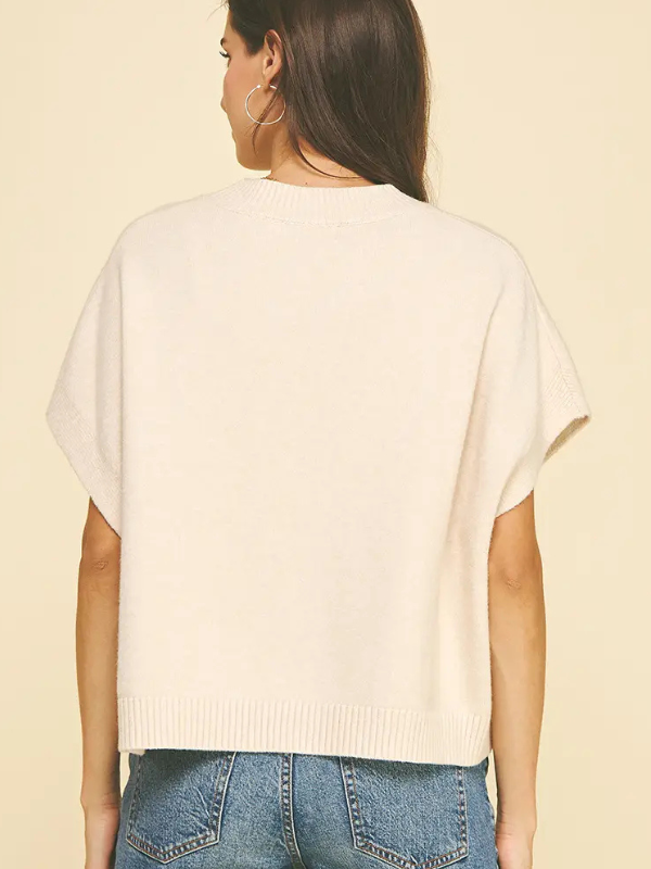 Woman wearing a white sweater and blue jeans on a beige background
