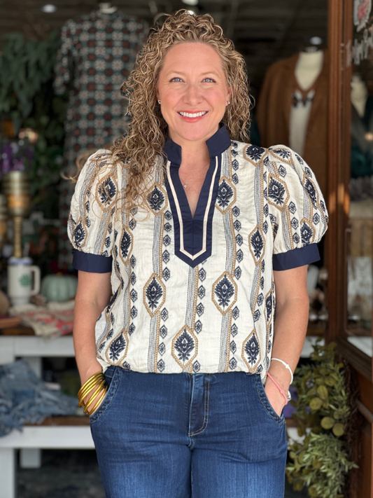 Woman wearing a patterned blouse and jeans in a store setting