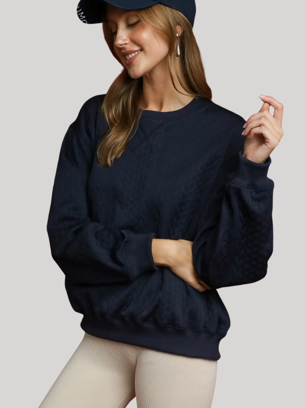 Woman wearing a navy blue sweater and cap on a light gray background