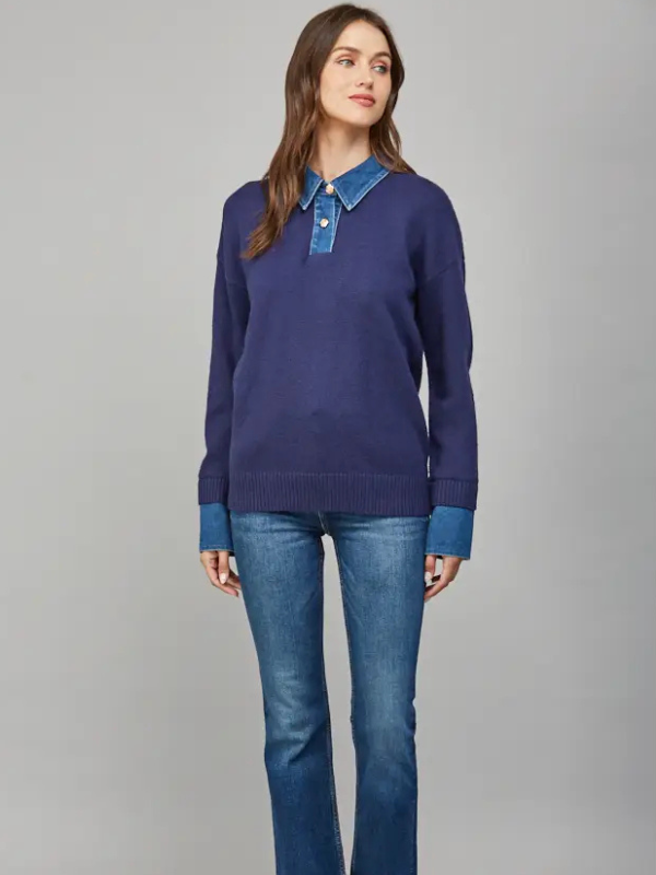 Woman wearing a blue sweater with a collar and jeans on a gray background