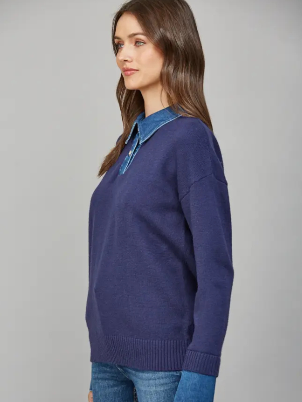 Woman wearing a blue sweater with a denim collar against a gray background